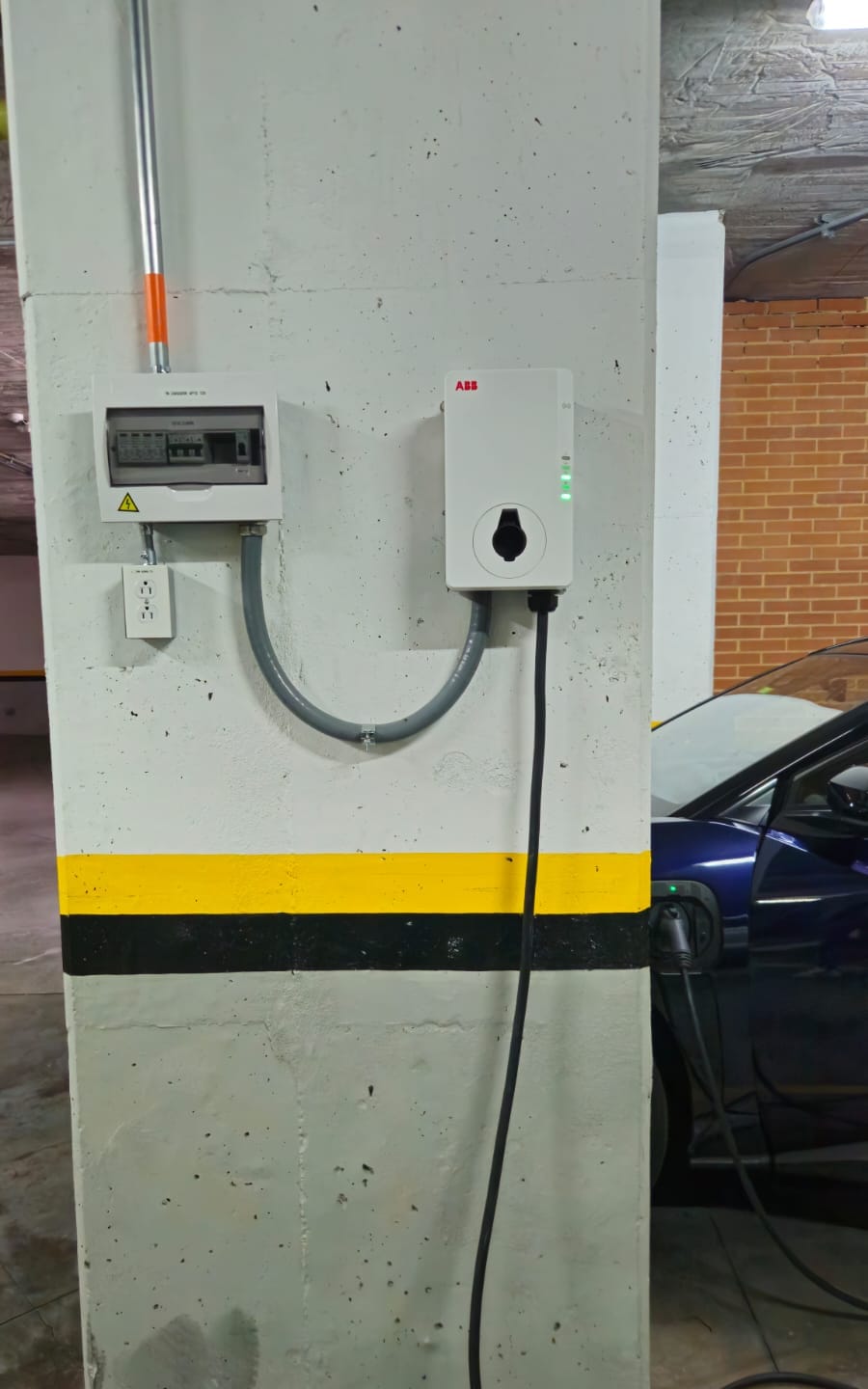 Cargador de pared cargando un vehículo eléctrico en un parqueadero residencial